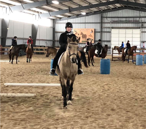 several riders playing in the indoor with their horses